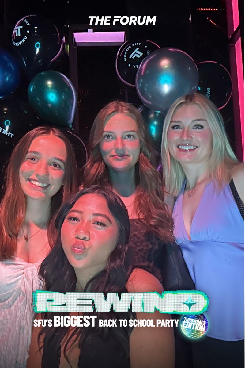Four friends smiling at the photobooth at Rewind, SFU's back to school party